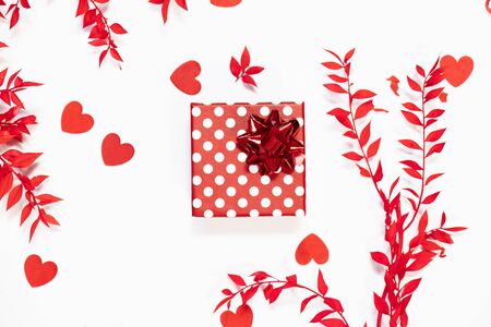 Spring frame with red leaves paper hearts and a gift box on white background. Flat lay, top view overhead layout place for text. Valentine's day holiday backgroundの写真素材