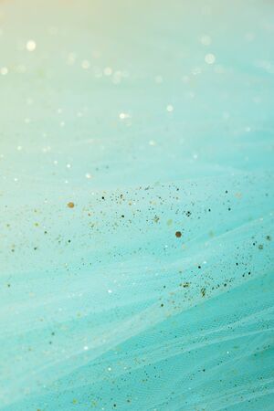 Feminine turquoise fabric tutu tulle skirt close up texture background with golden glitterの写真素材