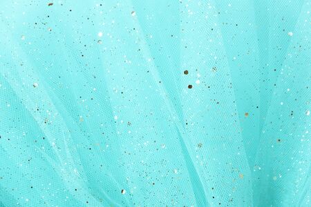 Feminine turquoise fabric tutu tulle skirt close up texture background with golden glitterの写真素材