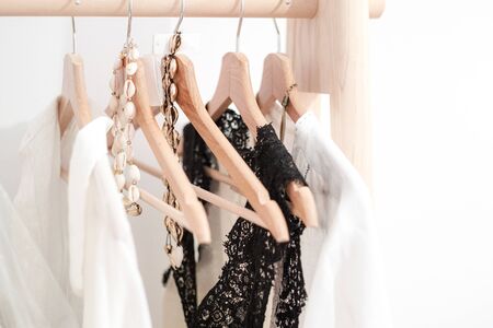 Detail of white clothes hanging on wooden hangers in a fashion store or home closetの写真素材