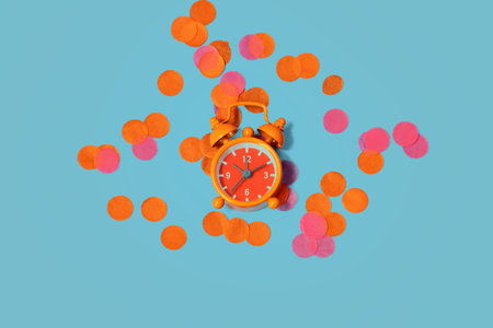 Vintage alarm clock among the multicolored confetti as concept for celebrating