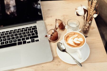 Coffee cup and laptop for business, Selective focus on cappuccino coffeeの写真素材