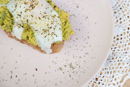 Whole wheat toasted bread with avocado and poached egg on a plate top viewの写真素材