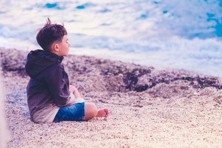 little boy Child meditating on the beachの写真素材