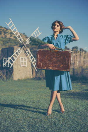 Young woman walking with suitcase in the field.の写真素材