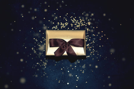 Christmas golden present with ribbon glitter sparkles background top view