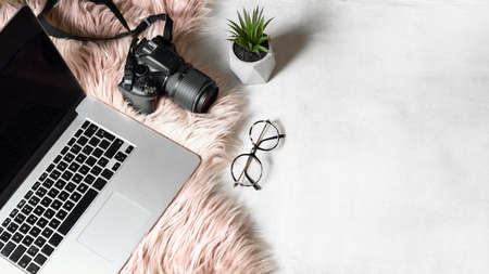 flat lay of workspace with laptop eyeglasses photo camera on white backgroundの写真素材