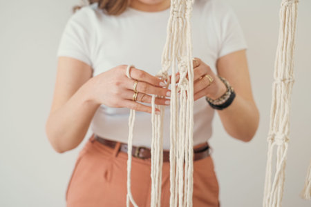 Womens hands weave a flower pot holders in macrame pattern in Boho style.
