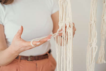 Womens hands weave a flower pot holders in macrame pattern in Boho style.の写真素材