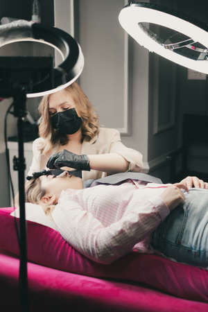 Cosmetologist applying permanent make up eyebrows for a clientの写真素材