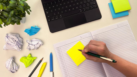 A workspace with a laptop, notepad, brightly colored sticky notes, and stationery. Concept for...
