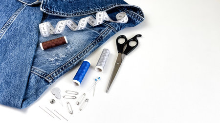 Denim with thread, scissors, pins, and a measuring tape. The concept of handicrafts, creativity, and...