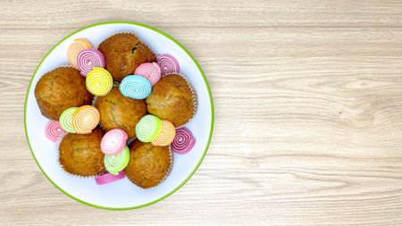 Homemade cupcakes with colorful marmalade on white plate, top view, wooden background, sweet dessert...