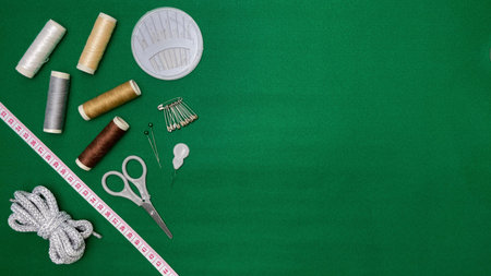 A composition with sewing accessories: thread, scissors, needles, pins, and a measuring tape on a...