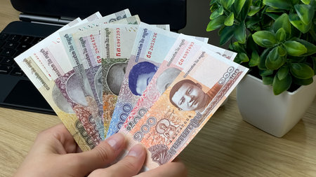 A man holds Cambodian riel banknotes of various denominations. Suitable for topics such as travel,...