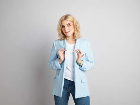 Blonde stands against the background of a light wallの写真素材