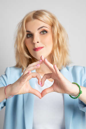 Girl blonde shows heart with her handsの写真素材