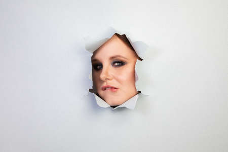 girl with makeup looks through a hole in the sheet, abstraction, backgroundの写真素材