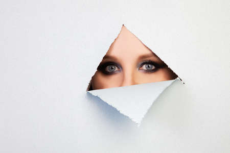 girl with makeup looks through a hole in the sheet, abstraction, backgroundの写真素材