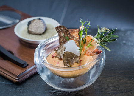 Pink mousse for vegetables with a crouton of seeds in a transparent container, decorated with slices of black truffle, shrimps and a sprig of rosemary.の写真素材