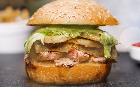 Delicious fried prawn and beef hamburger with salad and mayonnaise are served on a wooden wooden table. Side view. Close-up.の写真素材