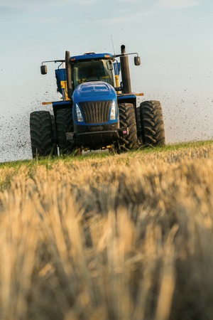 the tractor fertilizes the field with manure. A large trailer. Sowing. Agroindustry.Pole before sowing. Against the sky. yellow tractor.の写真素材