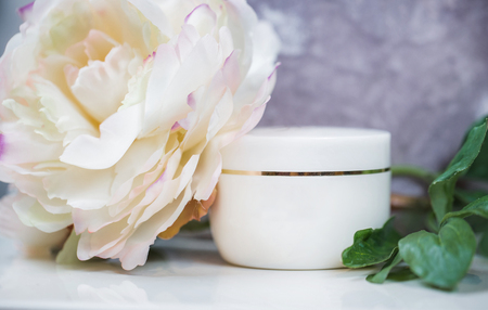 White cosmetic container on white, decorated with a large flowerの写真素材