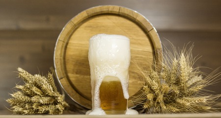 Beer glass and foam in the background of barrels wheatの写真素材