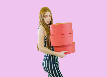 Attractive girl with red hair and bright makeup with gifts in her hands on an isolated background