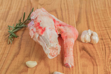 Raw meat bones of lamb with rosemary, raw lamb sticks, laid on a wooden cutting board. Close-up photoの写真素材