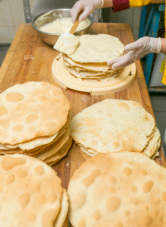 Cooking process. Preparation of multilayer cake. Cork for the domestic sorcerer. A big pile of fresh cakes on a wooden board. View from above.の写真素材