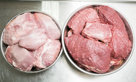 Selection of meat on the table with stainless steel, on the professional table of restaurant cuisine. Beef and pork are sorted by plates. Photo view from aboveの写真素材