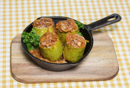 Zucchini stuffed with rice and meat - four pieces, served in a mini frying pan on a wooden plank. View from aboveの写真素材