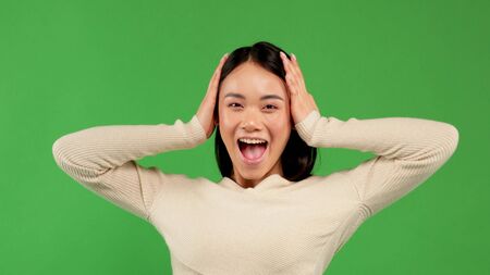 Happy attractive young asian girl holding her head in her arms and having fun shouting, positive emotions of women, victoryの写真素材