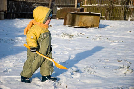 The boy with a shovel plays in the streetの写真素材