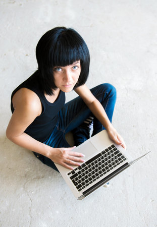 The young girl sits with the laptopの写真素材