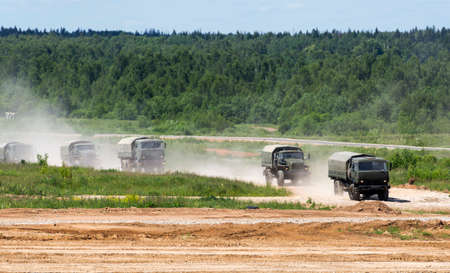 The military trucks go on a dirt roadの写真素材