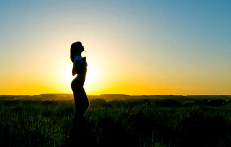 Silhouette of a young woman in front of a beautiful sunset.  Sensual girl with sun rising behind her.の写真素材