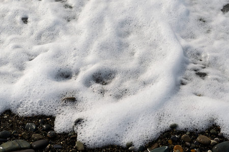 White sea foam on the pebble beach