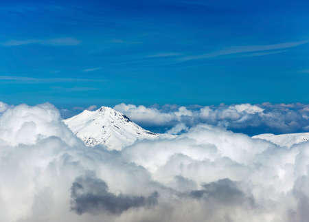 View through clouds at mountain peaks. Fantastic terrific natural landscape. Use for background, backdrop or design element in natural conceptの写真素材