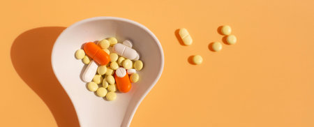 Assorted pharmaceutical medicine pills, tablets and capsules on a white spoon