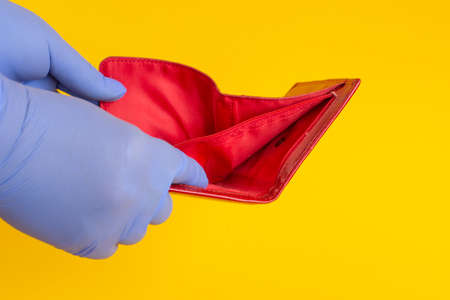 a girl in blue latex gloves holds an open red wallet. Empty purse.の写真素材