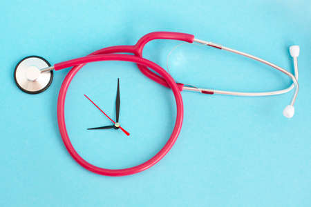 medical stethoscope and clock hands on a blue background. medical conceptの写真素材
