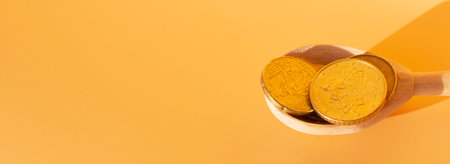 Wooden spoon with coins on a beige background. money saving conceptの写真素材