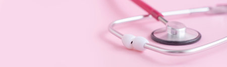 Stethoscope on a pink background with space for text. The concept of medicine