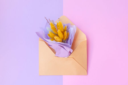 Purple field spring flowers in an envelope on a pastel pink background. background for greeting...