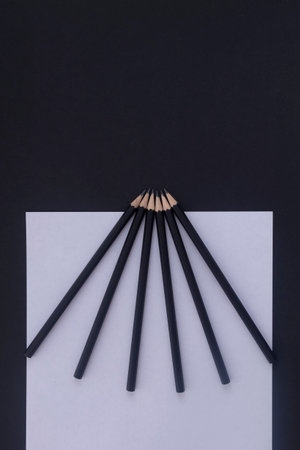 On a black table lie black pencils and white paper. Workplace. Flat lay. Business conceptの写真素材