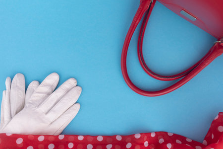 white gloves, red bag, red scarf on a blue background. Flat lay. Fashionable women's accessories.Fashion Concept. Stylish lady clothesの写真素材