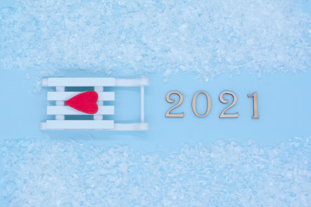 Happy New Year. Symbol from number 2021 and white sled with a red heart on a blue background. New year and merry Christmas concept.の写真素材