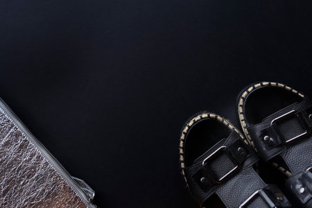 Black women's sandals, silver clutch on a black background. flat lay copy space. Fashionable women's accessories. Fashion Concept. Stylish lady clothesの写真素材